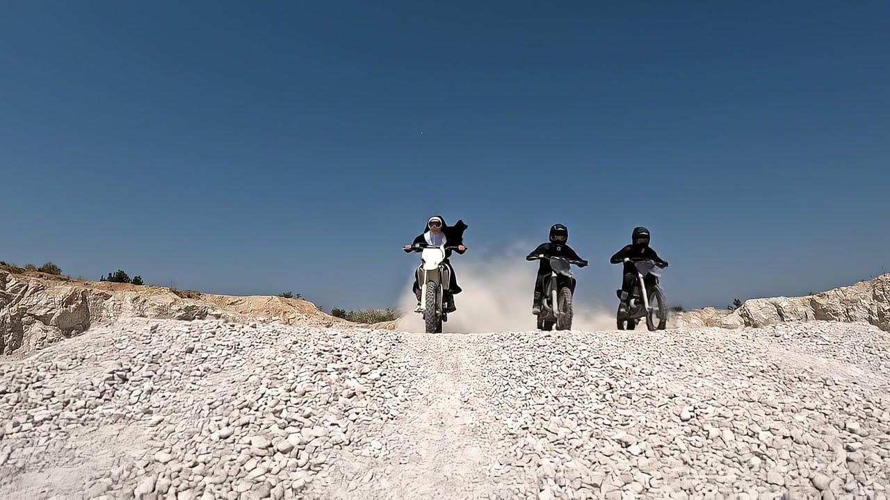Nuns on dirt bikes tear down a gravel road toward the camera