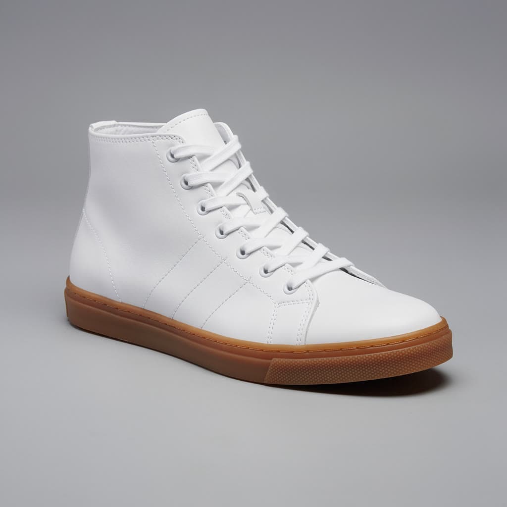 A white high-top sneaker with a gum sole on a plain grey backdrop