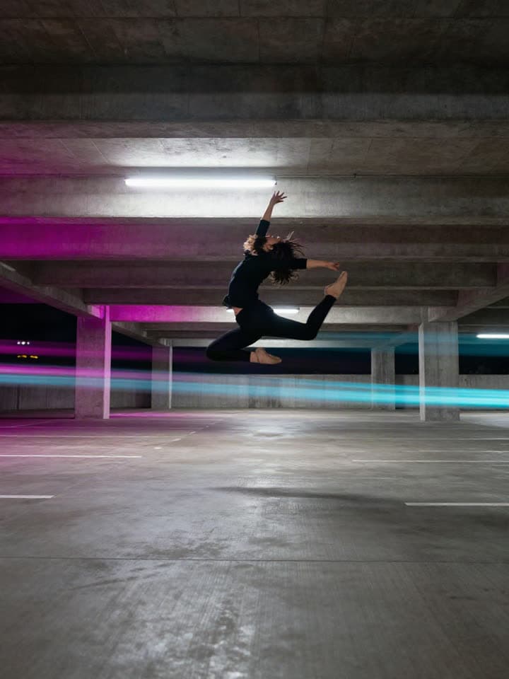 A dancer mid-leap in a neon garage, a real run on Leap