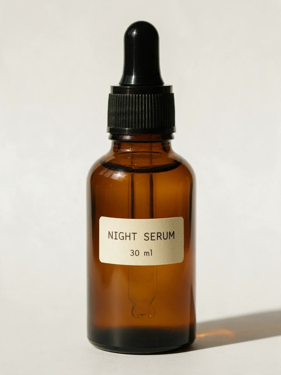 An amber dropper bottle labelled Night Serum on a white table
